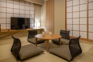 a room with a table and chairs and a tv at Oyado Kyoto Shinmachi in Kyoto