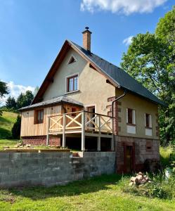 a house with a gambrel roof and a stone wall at Little Cottage No.100 in Vidochov