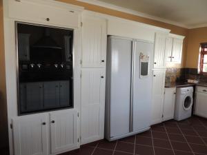 コルチェスターにあるNukakamma Guest Houseのキッチン(白いキャビネット、洗濯機、乾燥機付)