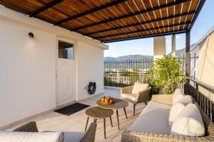 eine Terrasse mit einem Sofa und Stühlen auf dem Balkon in der Unterkunft Villy's Comfort Zone Apartments in Kalamata