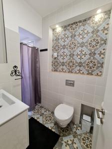 a bathroom with a toilet and a tile wall at Suite4u in Eilat