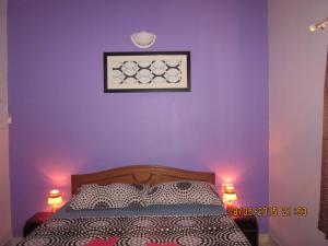 a bedroom with a purple wall with a bed and two lights at Apartment Du-2 Candolim in Candolim