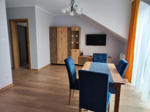 a dining room with a table and blue chairs at Villa Leofal in Suwałki
