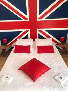 a bed with red pillows and a british flag on the wall at Chez Titian Vue sur le Mont St Michel in Pontaubault