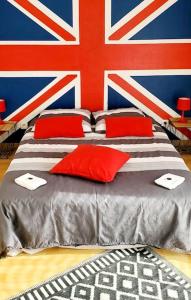 a bed with red pillows and a british flag at Chez Titian Vue sur le Mont St Michel in Pontaubault