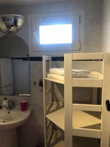 a small bathroom with a sink and a shelf with towels at Chez Titian Vue sur le Mont St Michel in Pontaubault