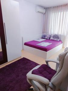 Piccola camera con letto, sedia e materasso viola. di Modern apartment in Burgas a Burgas