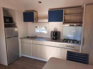 eine kleine Küche mit Spüle und Kühlschrank in der Unterkunft Mobil-home (Clim)- Camping Narbonne-Plage 4* - 011 in Narbonne-Plage