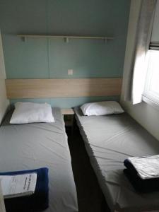two beds in a small room with at Mobil-home (Clim)- Camping Narbonne-Plage 4* - 011 in Narbonne-Plage