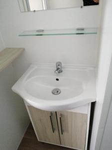 ein weißes Waschbecken mit einem Glasregal darüber in der Unterkunft Mobil-home (Clim)- Camping Narbonne-Plage 4* - 011 in Narbonne-Plage