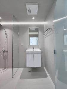 a white bathroom with a sink and a shower at White window sea in Hengchun