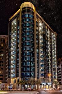 a tall building at night with its lights on at Icon Delux Hotel Apartments Al Barsha - Formerly Abidos in Dubai