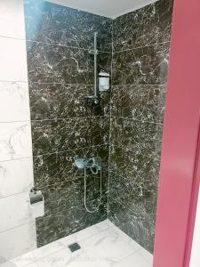 La salle de bains est pourvue d'une douche et d'un mur en marbre noir. dans l'établissement Şirin Apart, à Çorum