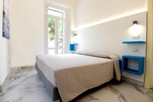 a white bedroom with a bed and a tv at Depandance Caramare in Cala Gonone