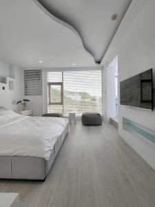 a white bedroom with a large bed and a flat screen tv at White window sea in Hengchun