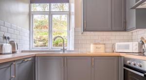 a kitchen with gray cabinets and a sink and a window at Bibby Lot in Rusland