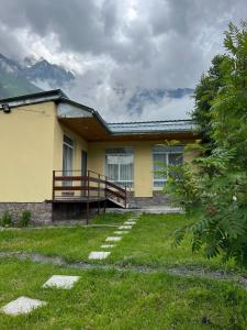 una casa amarilla con un banco en el patio en Mountain KAZBEGI Apartment, en Kazbegi
