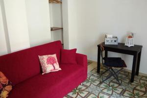 un divano rosso con cuscino rosa accanto a una scrivania di Appartamento centralissimo a Mottola