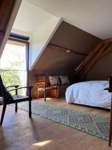 ein Schlafzimmer mit einem Bett, einem Stuhl und einem Fenster in der Unterkunft La Ferme de Châtenoy - Le Mouton Noir in Châtenoy