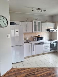 ポビエロボにあるApartamenty Agaの白い家電製品と壁掛け時計付きのキッチン