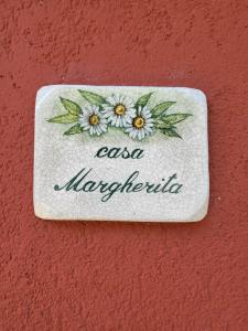 ein Schild an einer roten Wand mit Blumen drauf. in der Unterkunft Casa Margherita - bike friendly in Verbania