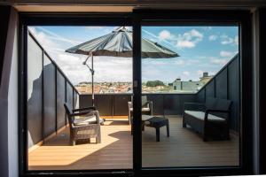 einen Balkon mit Sonnenschirm, Couch und Stuhl in der Unterkunft Casa da Perafita /Matosinhos, 2 Km from the beach in Perafita