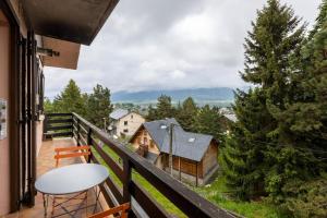 einen Balkon mit einem Tisch, Stühlen und Bäumen in der Unterkunft La Rose de Lou - Grand duplex avec vue montagne in Bolquere