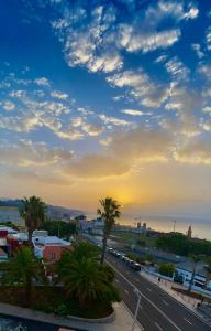 a sunset over a city with palm trees and a road at Apartamento de la Candelaria I in Santa Cruz de Tenerife