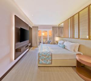 ムンバイにあるザ リゾートのベッドとテレビが備わるホテルルームです。
