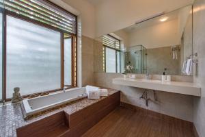 a bathroom with a tub and a sink and a window at SaffronStays Miraya - Nature Retreat, Pool, Games, Bar in Alibaug in Alibaug