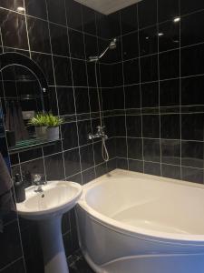 a bathroom with a white tub and a sink at Tallinn Street Apartment in Kuressaare