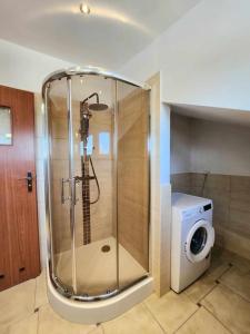 y baño con ducha y lavadora. en Cozy Apartament Country 6persons close to airport en Cracovia