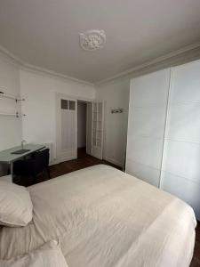 a bedroom with a large white bed and a desk at Charmant Appartement Parisien in Paris