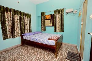 a small bed in a room with blue walls and curtains at Phoenix Holiday Home in Kanyakumari
