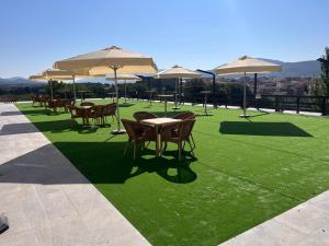 Hospedium Hotel Mirador de Gredos في إل باركو دي أفيلا: مجموعة من الطاولات والكراسي مع مظلات على عشب