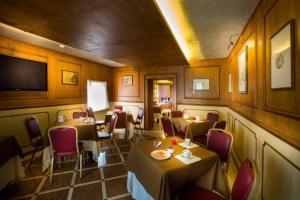 Hotel Camerlengo في Corridonia: مطعم بطاولات وكراسي وتلفزيون