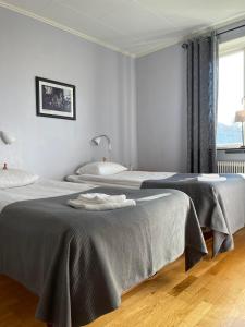 two beds in a white room with a window at Brålanda Hotell och Vandrarhem in Brålanda