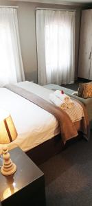 ein Schlafzimmer mit einem Bett und einem Tisch mit einer Lampe in der Unterkunft Villa Tuscana in Port Elizabeth