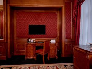 Habitación con escritorio y TV en una pared roja. en Hotel Koronny, en Zamość