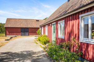 un granero rojo con una entrada al lado en Raftarp - Country side cottage in the woods en Sjöbo