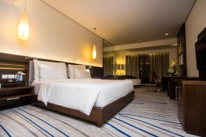 a hotel room with a large bed and a desk at Le Meridien Coimbatore in Coimbatore