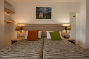 a bedroom with a large bed with colorful pillows at Hotel Del Pui in La Massana