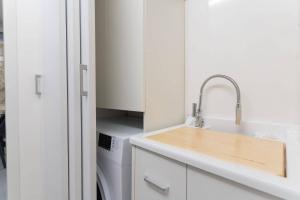 uma cozinha branca com um lavatório e uma máquina de lavar louça em Lovely Modern Apartment em Modica