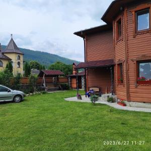 a house with a yard with a car parked next to it at Zatushok pid goroyu in Verkhovyna