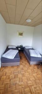 two beds in a room with a wooden floor at Monteurhaus in Hemer - Gemeinschaftsnutzung Küche und Bad in Hemer