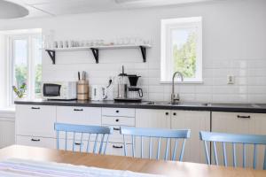 uma cozinha com armários brancos e cadeiras azuis em Jocksborg - Country side cottage in the woods em Sjöbo