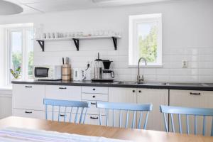 eine Küche mit weißen Schränken und blauen Stühlen in der Unterkunft Jocksborg - Country side cottage in the woods in Sjöbo + 9 Fotos