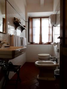 baño con 2 aseos, lavamanos y ventana en B&B Borgolecchi , Lecchi in Chianti, en San Sano