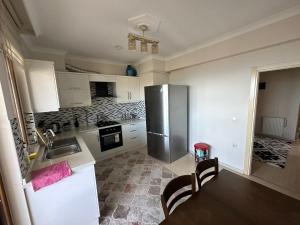 a kitchen with a refrigerator and a table and chairs at VIP DAİRE DENİZ MANZARALI in Degirmen