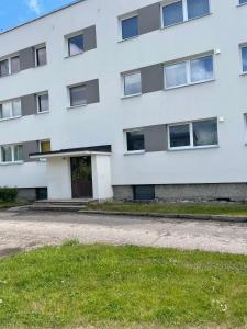 a white building with a door and grass at Tallinn Street Apartment in Kuressaare